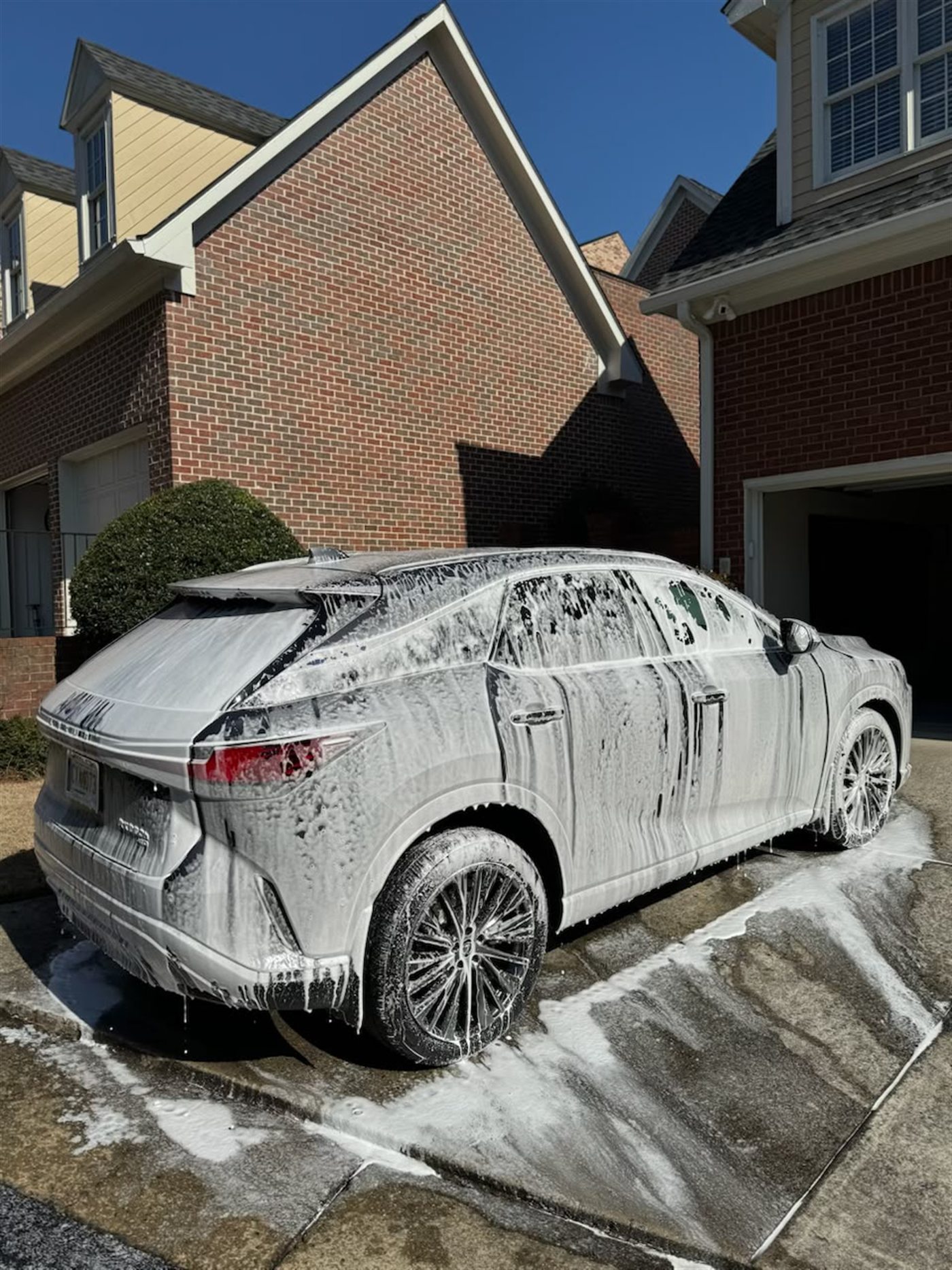 A Lexus RX completely covered in thick white snow foam during a wash