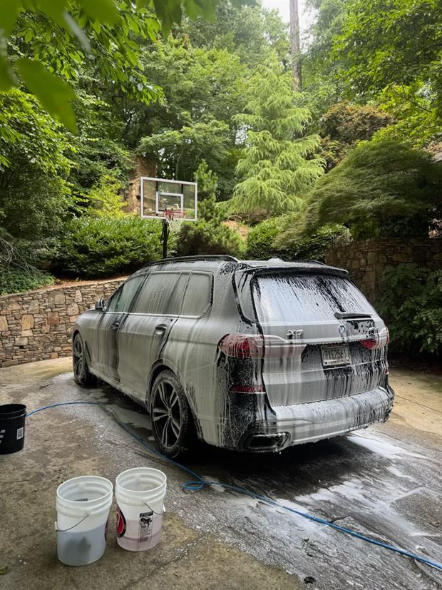 A large Mercedes-Benz GLS covered in foam on a driveway