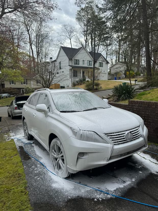 A Lexus RX buried in white foam in front of a house