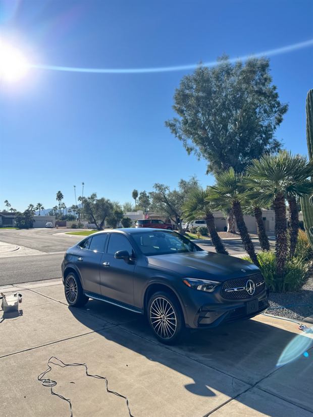 A dark Mercedes-Benz SUV clean on a driveway with sun flare overhead