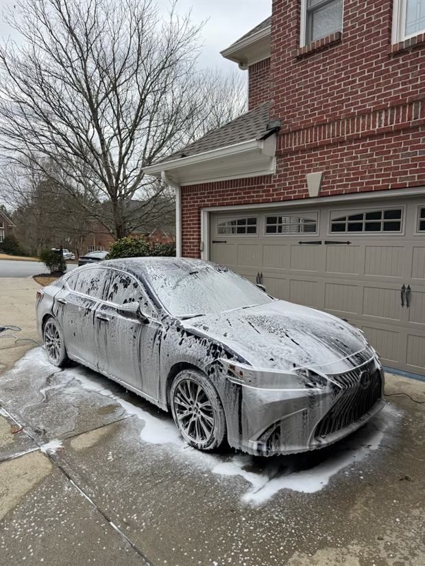 A sedan covered in white foam on a driveway