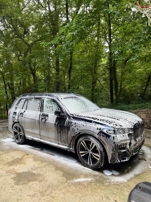A large BMW SUV covered in thick white foam